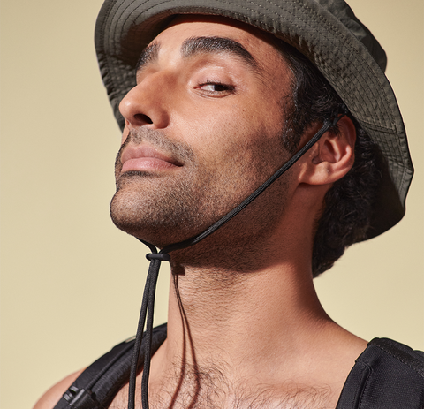 A person smirking while giving a side-eye wearing a bucket hat.