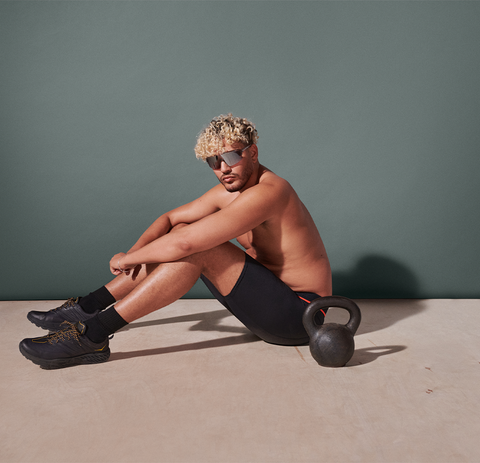 A person sitting down next to a kettle bell wearing the Kinetic HD Long Leg in Black.